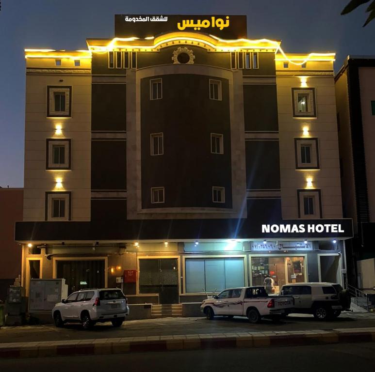 dwa samochody zaparkowane w nocy przed hotelem w obiekcie فندق نواميس للشقق المخدومه w mieście Chamis Muszajt