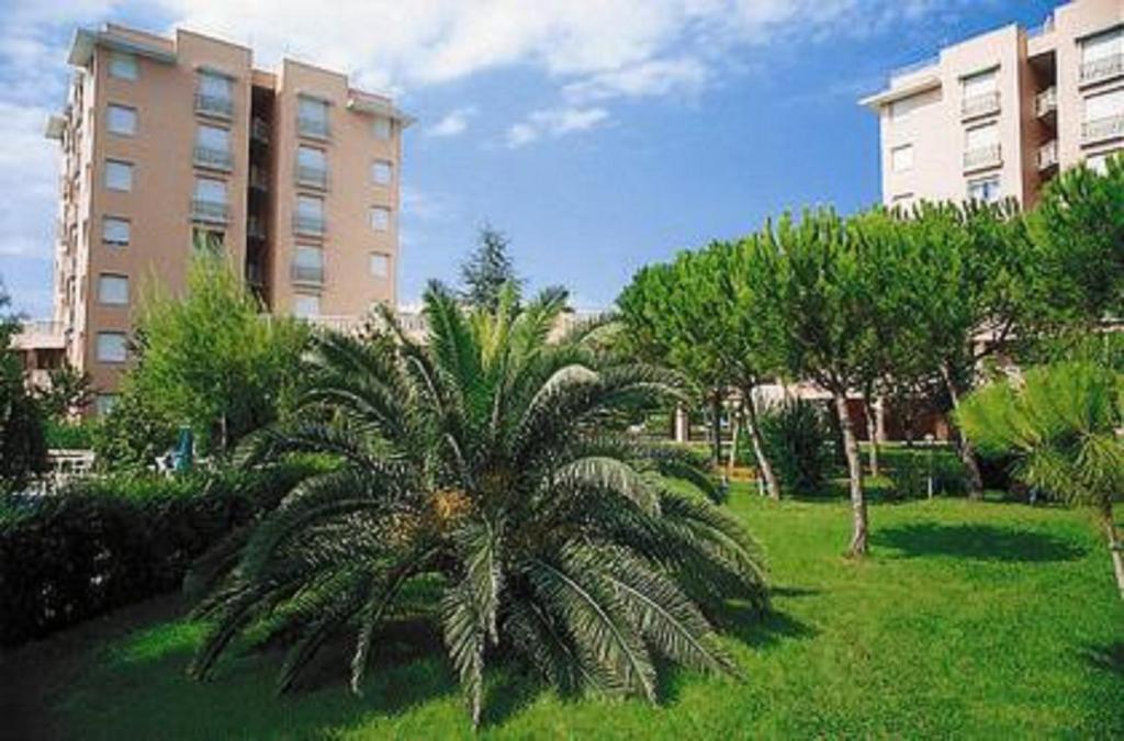 a palm tree in a park in front of a building at Trilo Conero, in residence con piscina ed aria condizionata vicino al mare in Marcelli