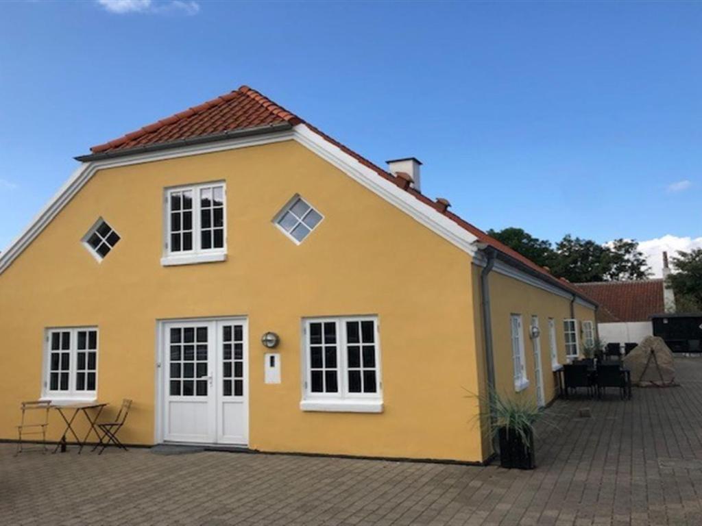 ein gelbes Haus mit weißen Türen und einer Terrasse in der Unterkunft Apartment Murtuz - 900m from the sea in NW Jutland by Interhome in Skagen