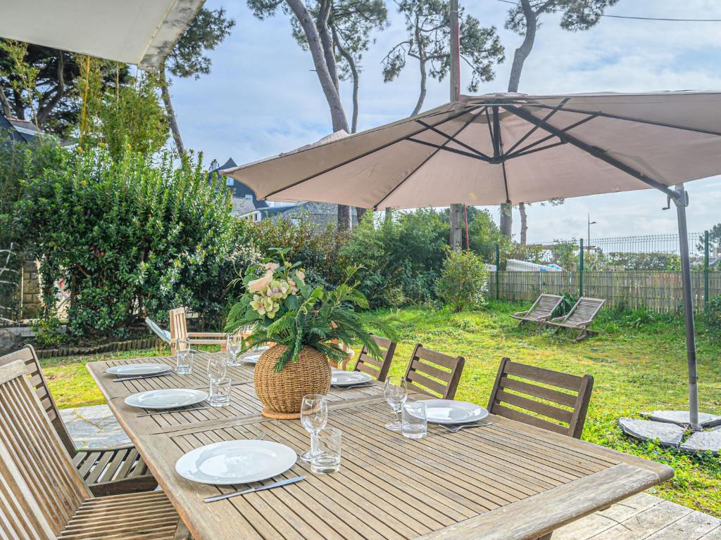 - une table en bois avec un parasol dans l'arrière-cour dans l'établissement Apartment La Voilerie - La Brigantine by Interhome, à Carnac