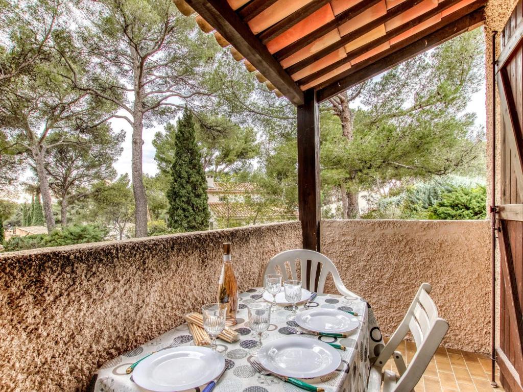 - une table avec des chaises et une bouteille de vin sur la terrasse dans l'établissement Studio Les Hauts du Port-3 by Interhome, à Saint-Cyr-sur-Mer