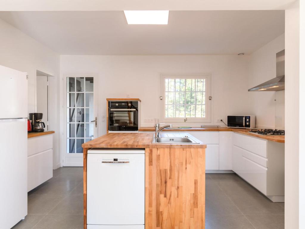 a kitchen with white cabinets and a wooden counter top at Holiday Home Les Chênes by Interhome in Lit-et-Mixe