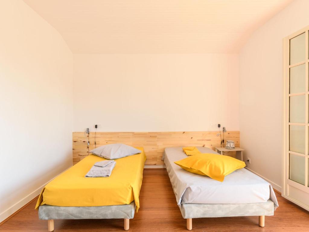 two beds in a room with white walls and wood floors at Holiday Home Les Chênes by Interhome in Lit-et-Mixe