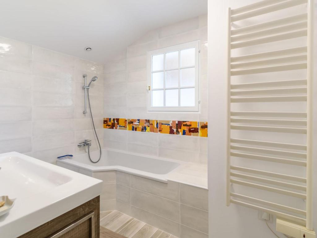 a white bathroom with a tub and a sink at Holiday Home Les Chênes by Interhome in Lit-et-Mixe