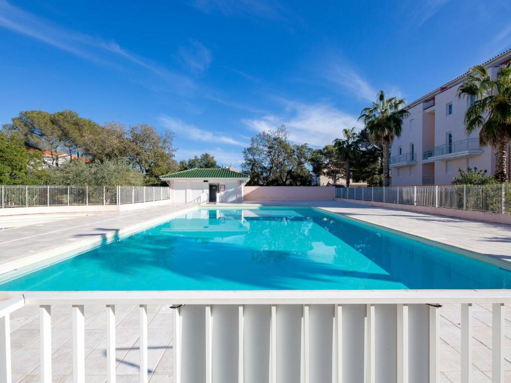 une piscine avec une clôture blanche et de l'eau bleue dans l'établissement Apartment Le Grand Parc-10 by Interhome, à Saint-Aygulf