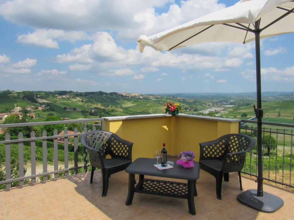 een patio met 2 stoelen, een tafel en een parasol bij Apartment Emilia Guest House by Interhome in Agliano Terme