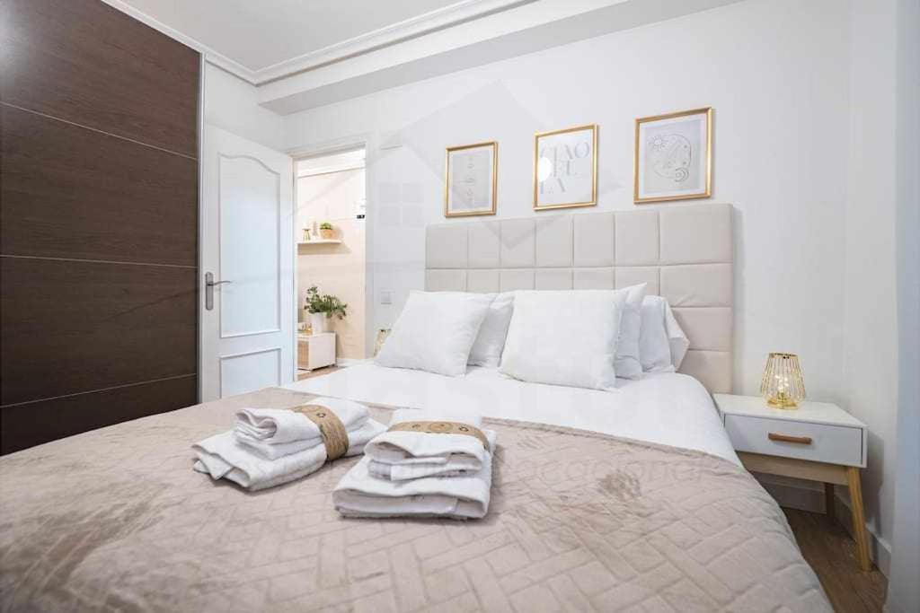 a white bedroom with a large bed with towels on it at La Muralla centro Oviedo in Oviedo