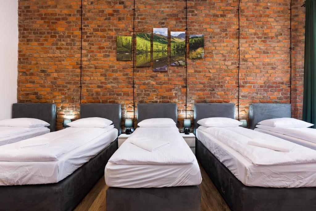 a room with four beds against a brick wall at Big flat for groups - for 13 pax, 100sq in Krakow