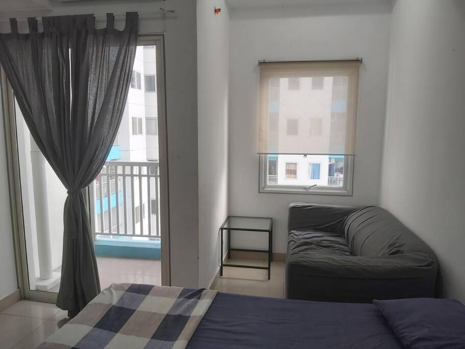 雅加達的住宿－The Nest Dipuri，一间卧室配有一张床、一张沙发和一个窗口