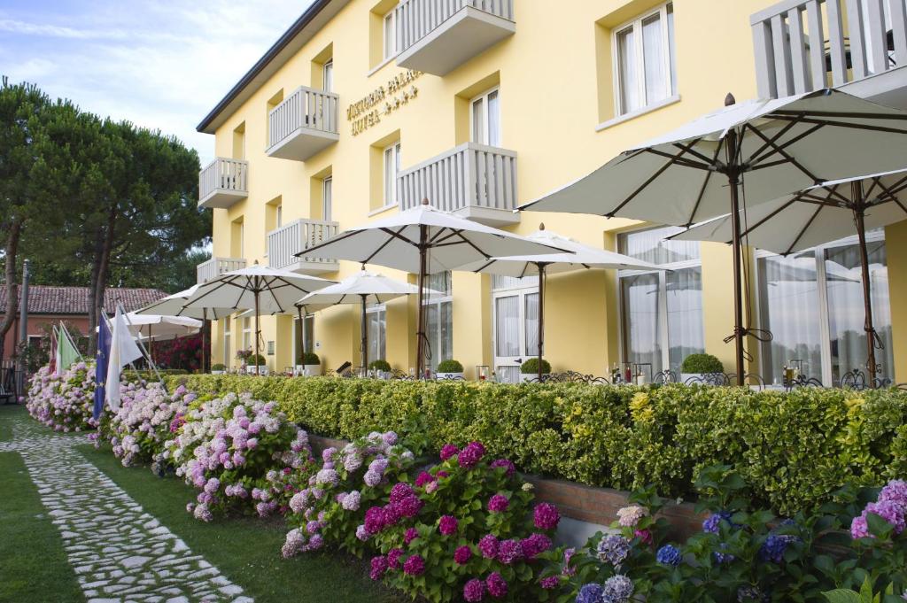 een hotel met parasols en bloemen voor de deur bij Viktoria Palace Hotel in Venetië-Lido