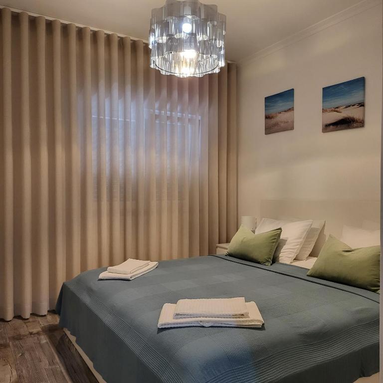 a bedroom with a large bed with a chandelier at Nandos Apartement in Costa da Caparica