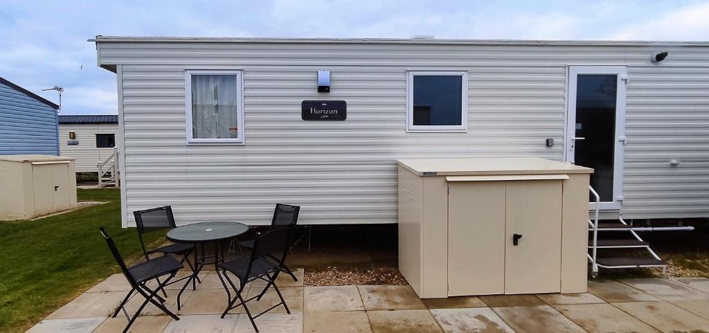 a small white trailer with a table and chairs at Golden Sands Pine Drive 53, 3 Bedrooms & Wi-fi in Mablethorpe