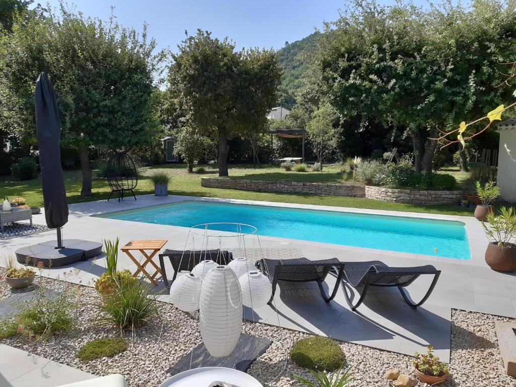 - une piscine avec une table et des chaises à côté dans l'établissement Le Patio 4*. SPA, jardin, piscine en provence, proche Grignan, à Saint-Paul-Trois-Châteaux