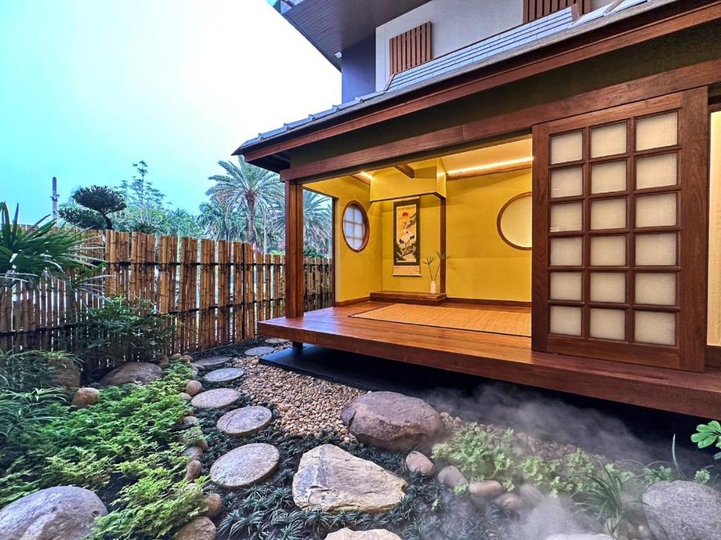 a small yellow building with a deck in a yard at Kinnotel in Phrae