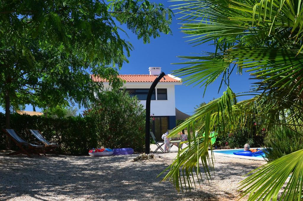 a house with a swimming pool and palm trees at Trendy casa de Ferias in Monte da Pedra Alva