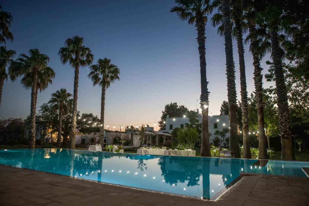 una piscina di fronte alle palme di notte di Parco Degli Aranci a Cutrofiano