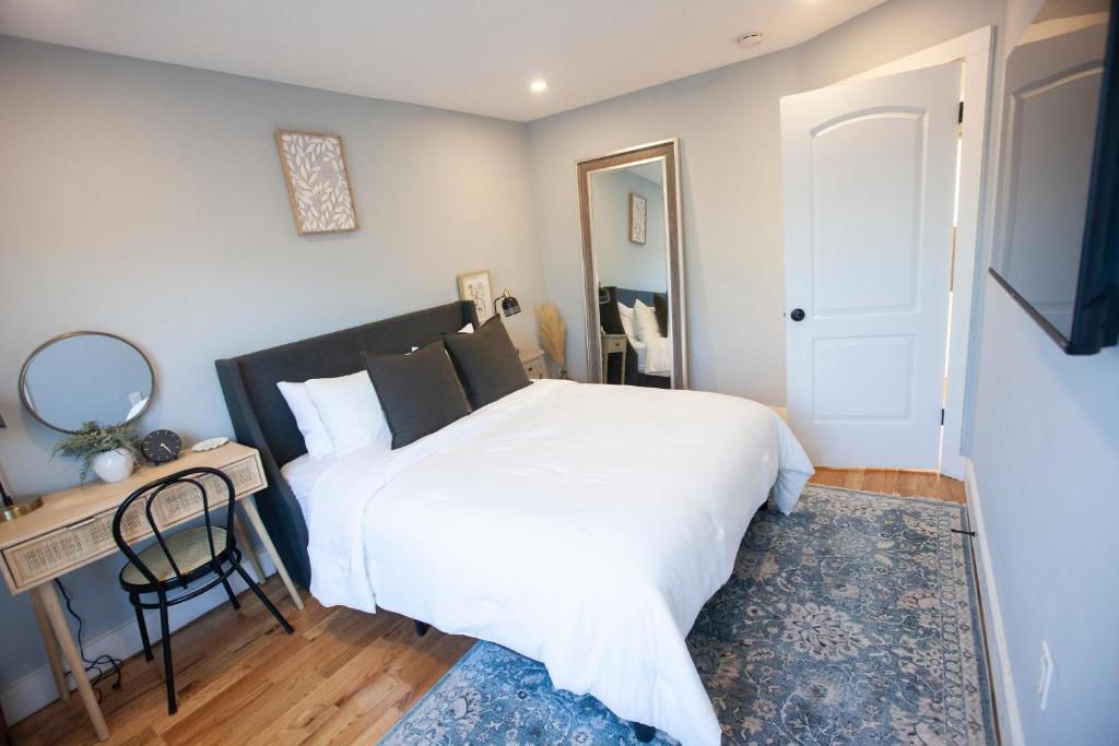 Un dormitorio con una gran cama blanca y una mesa en Alafia- Cozy JFK Area Home - This property is a hosted property meaning the host live on site en Locust Manor
