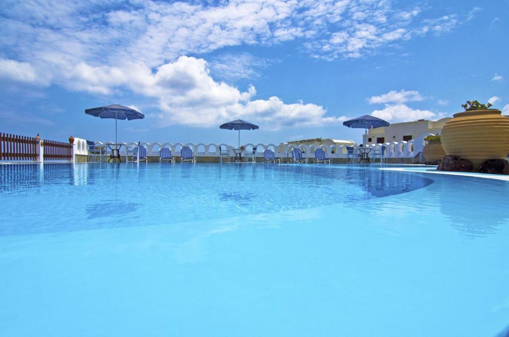 une grande piscine avec des chaises et des parasols dans l'établissement Agapi Villas, à Karterados