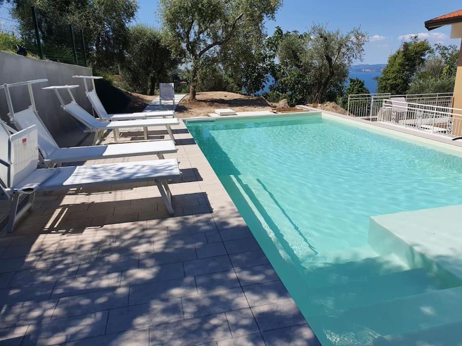 a swimming pool with lounge chairs and a swimming pool at Villa Malù - APT Luisa Piscina e vista lago in Torri del Benaco
