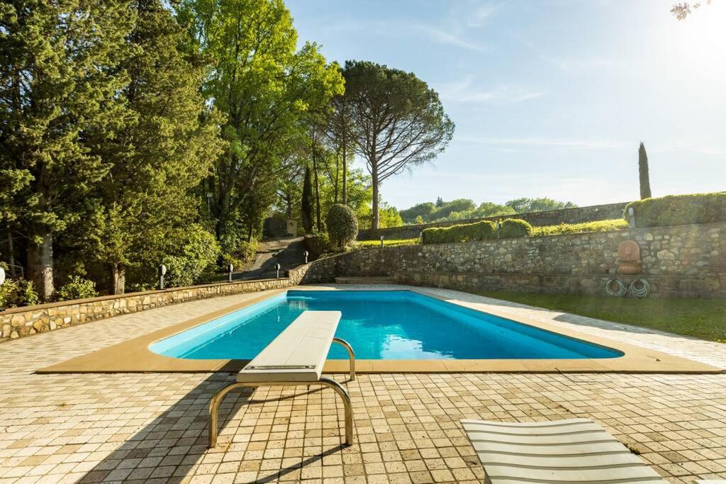 Badia A Passignano的住宿－Il Poggiolino - Tuscan villa located in Chianti's hills，游泳池旁的长凳