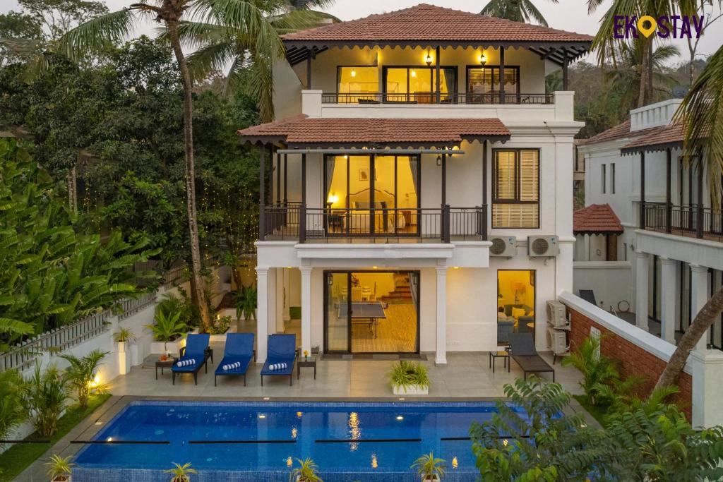 a house with a swimming pool in front of a house at EKOSTAY Luxe - Jade Villa I Infinity Pool I Paddy Field Views in Candolim
