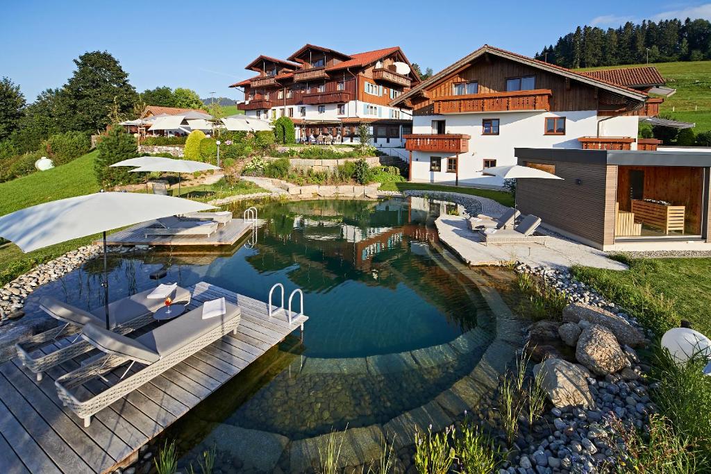a swimming pool in front of a house at Natur- & Genießerhotel Der Birkenhof in Oberstaufen