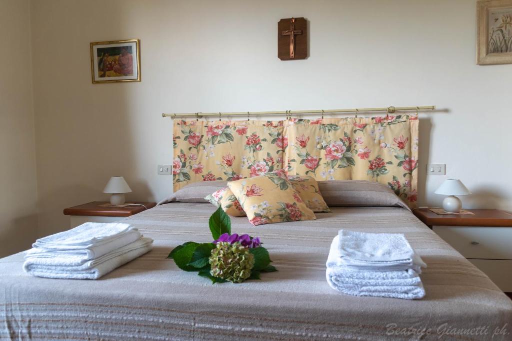 - une chambre avec un lit, des serviettes et des fleurs dans l'établissement Appartamento per Vacanze Domus Lunae, à Luni