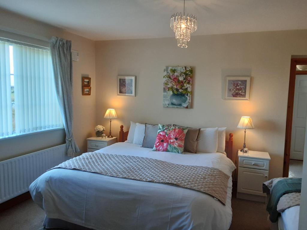Un dormitorio con una cama grande y una lámpara de araña. en Hawthorn Lodge, en Belturbet