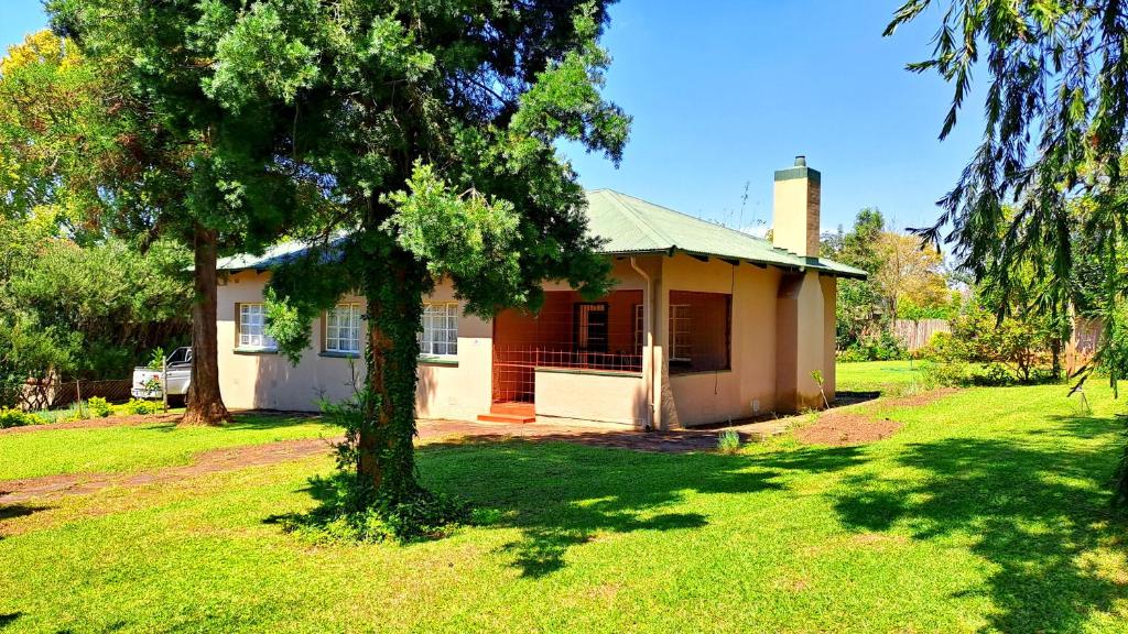 a small house with a tree in the yard at Pine Forest Cottage in Sabie