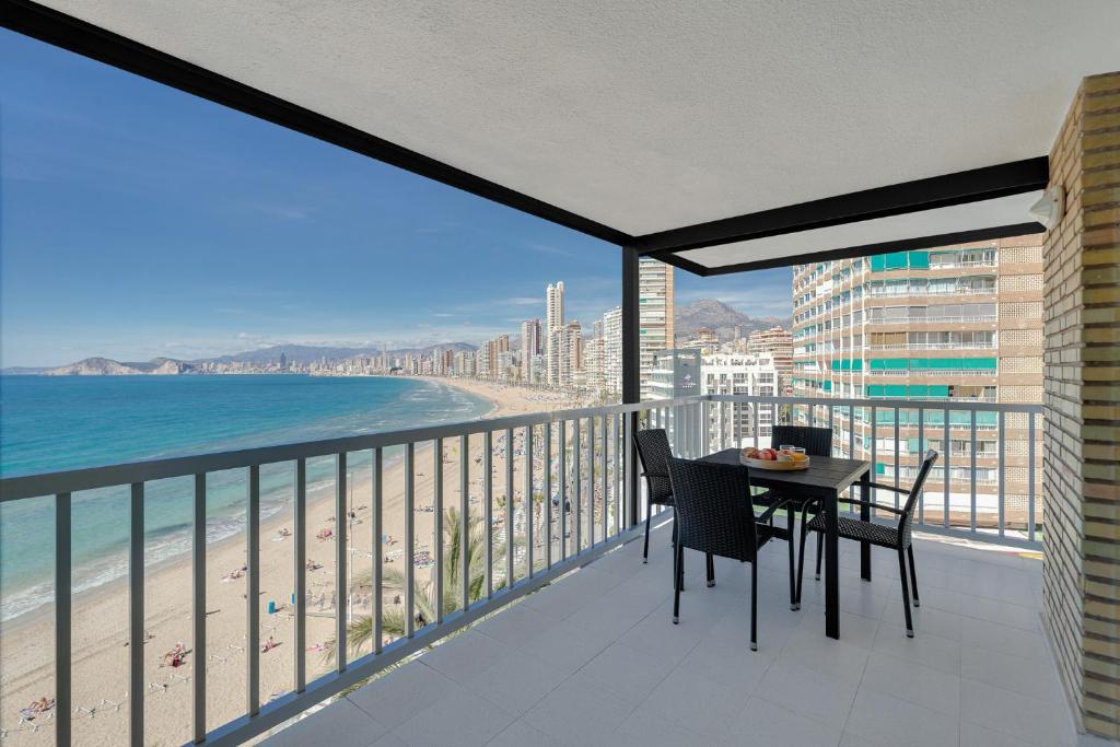 a balcony with a table and chairs and the beach at Levante Sunset Front line apartment Almadraba in Benidorm