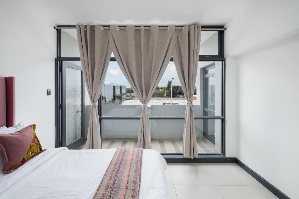 a bedroom with a bed and a large window at Rest on Millvale guest house in Cape Town