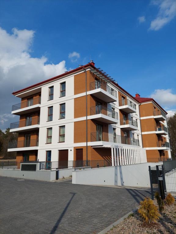 ein orangefarbenes und weißes Apartmenthaus mit einem Parkplatz in der Unterkunft Marel-Apartments Willa Fonte - apartament 8 in Polanica-Zdrój