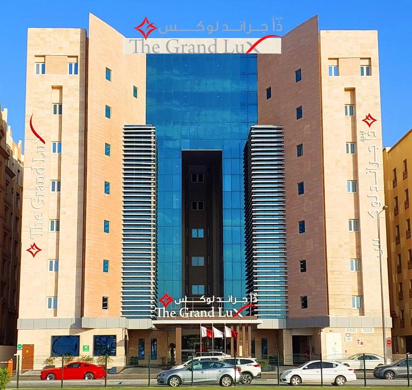 un gran edificio con coches estacionados frente a él en The Grand Lux Hotel, en Doha