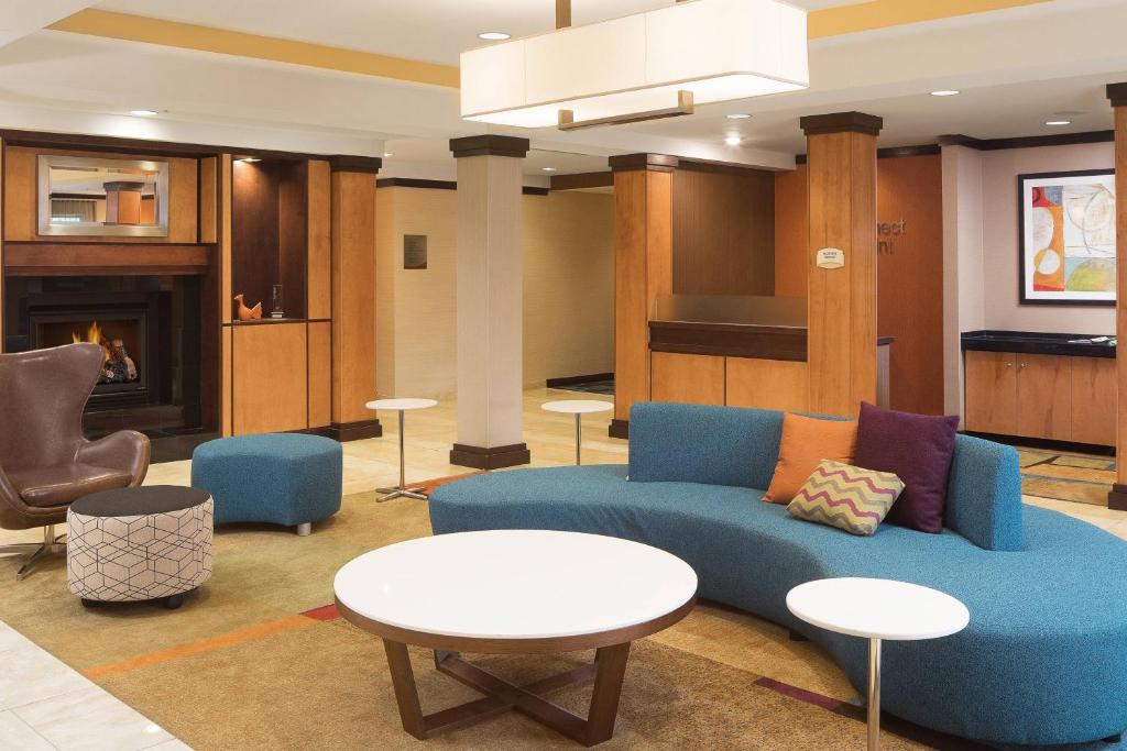 a lobby with a blue couch and tables and a fireplace at Fairfield Inn and Suites by Marriott Conway in Conway