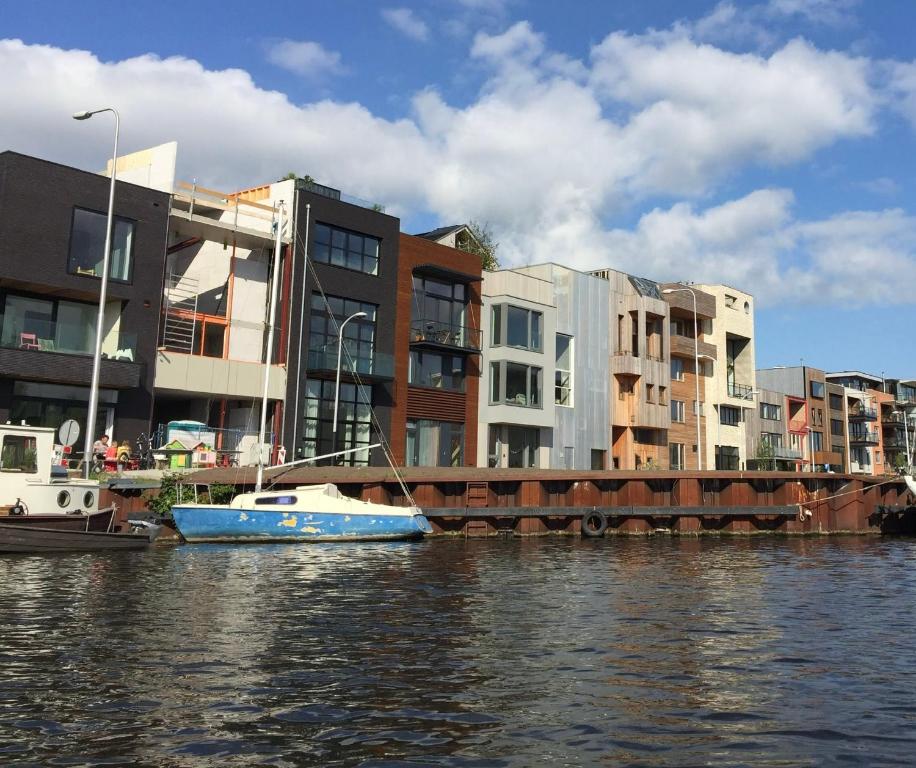 ein blaues Boot im Wasser neben einigen Gebäuden in der Unterkunft Industriële WOW! Private studio 35m2 in Amsterdam