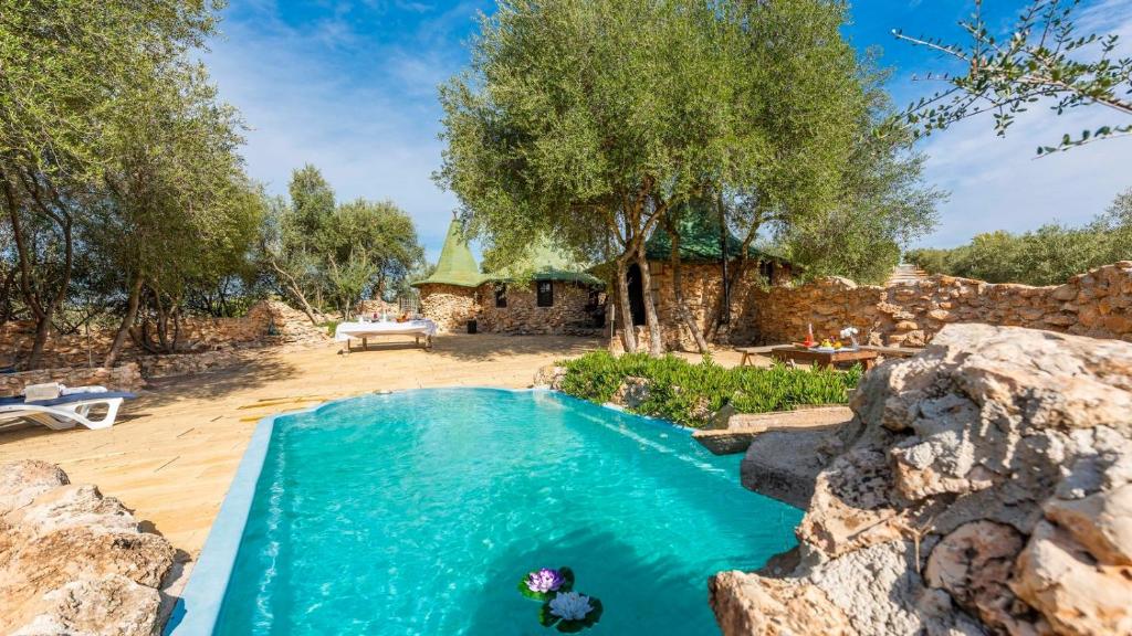 ein Pool in der Mitte eines Gartens mit einem Haus in der Unterkunft Casa de Piedra La Laguna de Tiscar Puente Genil by Ruralidays in Puente-Genil