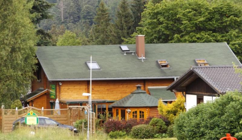 una casa de madera con un coche aparcado delante de ella en Ferienhaus-Hotel "Zur Grünen Oase", en Adelmannsfelden