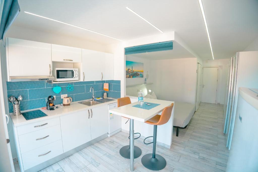 a kitchen with white cabinets and a table in it at Piso Paraíso vicino al mare in Maspalomas