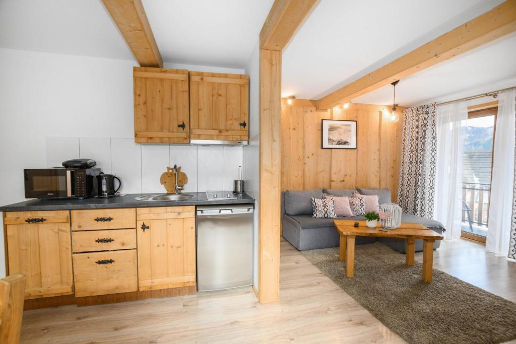 a kitchen and living room with a couch and a table at Zakopiańska Osada Apartamenty in Zakopane