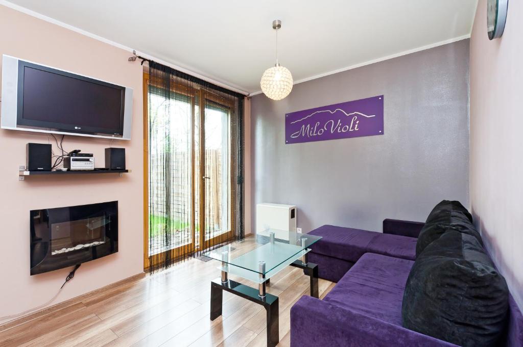 a living room with a purple couch and a tv at Apartamenty Sun & Snow Poronin in Poronin