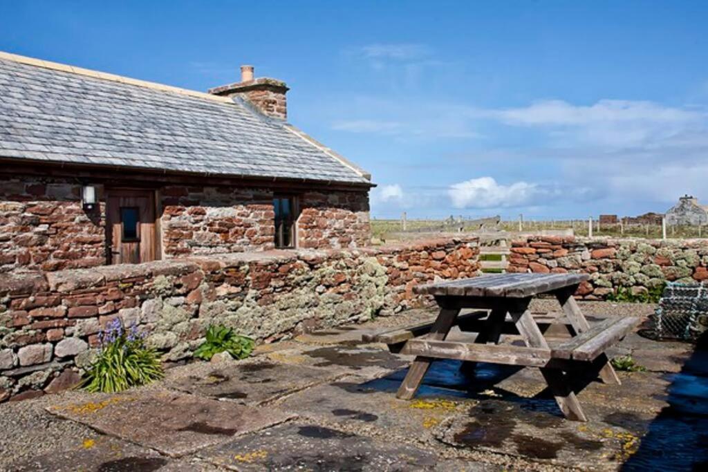 a picnic table in front of a stone building at The Ruah - Clifftop Retreat in Whitehall