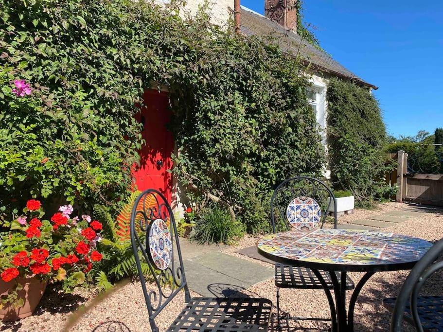 dos sillas y una mesa frente a un edificio en Charming, rustic & well equipped garden cottage en Alyth