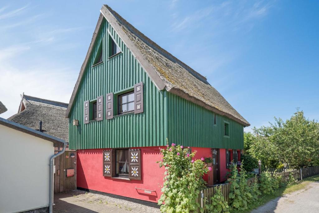 une maison rouge et verte avec un toit vert dans l'établissement Töpferweg 06 Ferienwohnung Tine, à Ahrenshoop