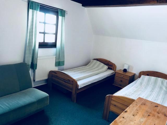 a room with two beds and a chair and a window at Pensjonat Stokłos in Zieleniec