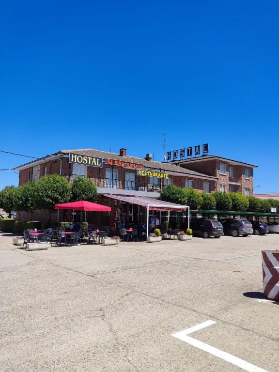 a hotel with tables and umbrellas in a parking lot at HOSTAL EL CHOCOLATERO in Castildelgado