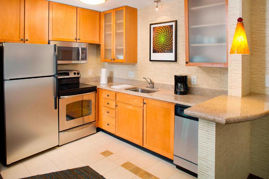 a kitchen with wooden cabinets and a stainless steel refrigerator at Residence Inn by Marriott Roanoke Airport in Roanoke
