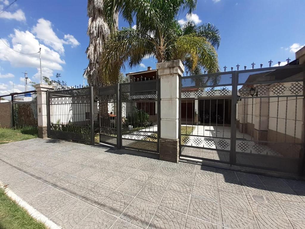 une clôture devant une maison avec un palmier dans l'établissement Hospedate en nuestro hogar y disfruta unas lindas vacaciones en Termas de Rio Hondo, à Termas de Río Hondo