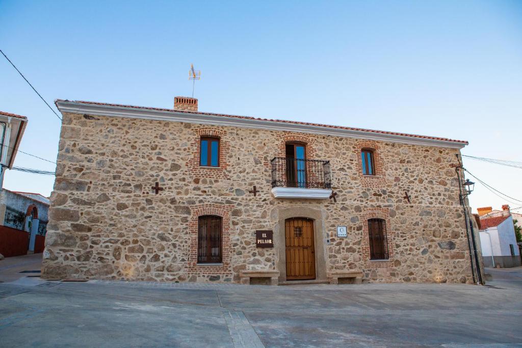 - un bâtiment en pierre avec une porte et un balcon dans l'établissement El Pelaor, à Benquerencia