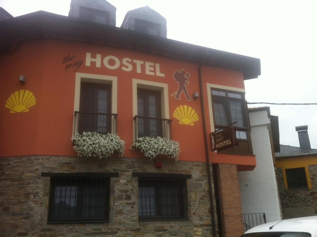 een oranje gebouw met ramen en bloemen erop bij The Way Hotel Molinaseca in Molinaseca
