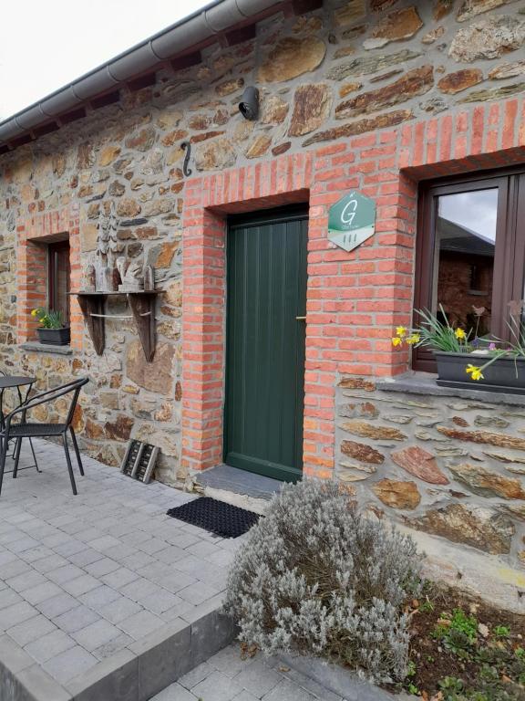 a green door on the side of a brick building at Le Fournil Gîte Rural in Trois-Ponts